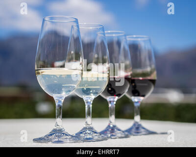 Avec quatre verres, deux rouges et deux avec des vins blancs servis en dégustation dans l'un des vignobles à Winelands, Afrique du Sud. Banque D'Images