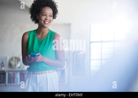 Portrait de femme aux cheveux noirs frisés holding mobile phone Banque D'Images