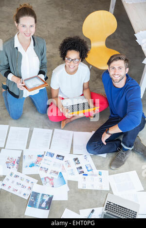 Portrait de trois jeunes gens assis sur le sol et travailler ensemble Banque D'Images