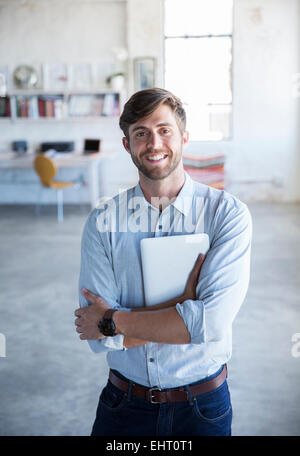 Portrait of young man standing in studio with digital tablet Banque D'Images