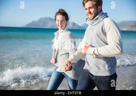 Young couple holding hands and walking on beach Banque D'Images