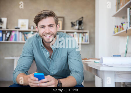 Portrait de jeune homme assis avec un téléphone mobile Banque D'Images