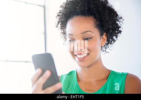 Portrait de femme aux cheveux noirs frisés holding mobile phone Banque D'Images