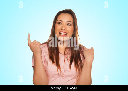 Portrait of smiling young woman pointing up Banque D'Images