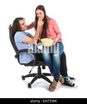 L'homme et la femme assis ensemble dans un fauteuil eating pop corn, isolé sur fond blanc Banque D'Images