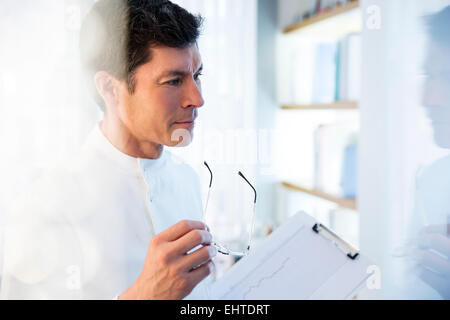 À l'écart,Vue de l'homme en tenue de laboratoire verres et graphique Banque D'Images