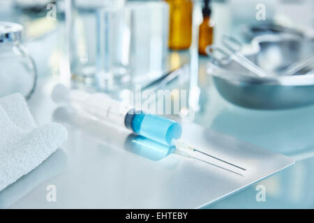 Avis de seringue avec le liquide bleu sur une table en verre in laboratory Banque D'Images