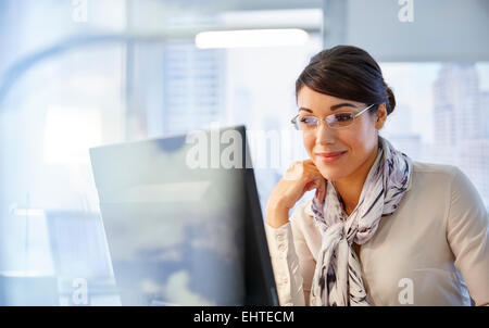 Female office worker sitting at desk using computer Banque D'Images