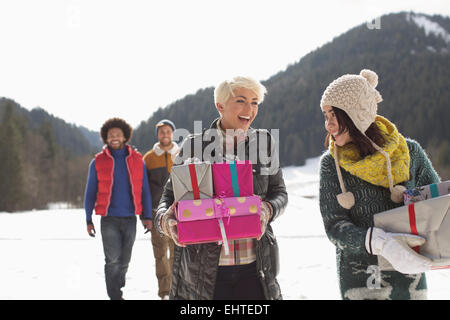 Les amis carrying Christmas gifts in snow Banque D'Images