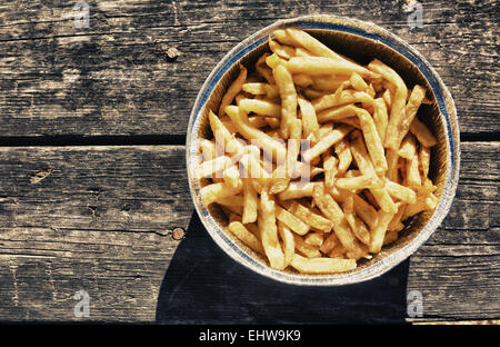 Les frites dans du papier aluminium bac. a servi plus vieille table de pique-nique en bois Banque D'Images