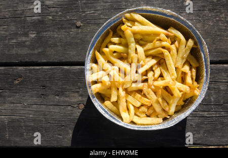 Les frites dans du papier aluminium bac. a servi plus vieille table de pique-nique en bois Banque D'Images