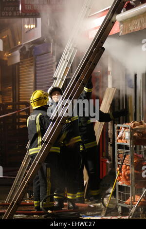 Ilford, Londres, Royaume-Uni. Mercredi 18 mars 2015. 11 sauvé du feu dans les appartements au-dessus d'une boutique à Ilford. Six pompiers de partout dans l'Est de Londres s'attaque à un incendie dans un immeuble d'appartements à Ilford, tôt ce matin. London Fire Brigade a signalé que six adultes et cinq enfants dont un bébé ont été secourus par les pompiers en utilisant des échelles. Il est signalé que l'incendie a éclaté dans un magasin ci-dessous les appartements. Banque D'Images