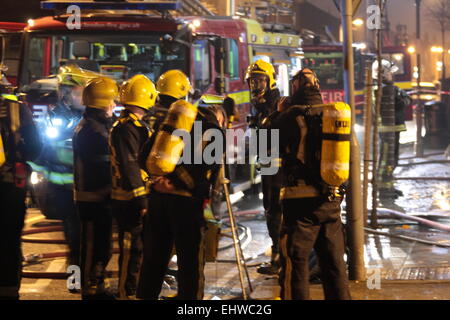 Ilford, Londres, Royaume-Uni. Mercredi 18 mars 2015. 11 sauvé du feu dans les appartements au-dessus d'une boutique à Ilford. Six pompiers de partout dans l'Est de Londres s'attaque à un incendie dans un immeuble d'appartements à Ilford, tôt ce matin. London Fire Brigade a signalé que six adultes et cinq enfants dont un bébé ont été secourus par les pompiers en utilisant des échelles. Il est signalé que l'incendie a éclaté dans un magasin ci-dessous les appartements. Banque D'Images