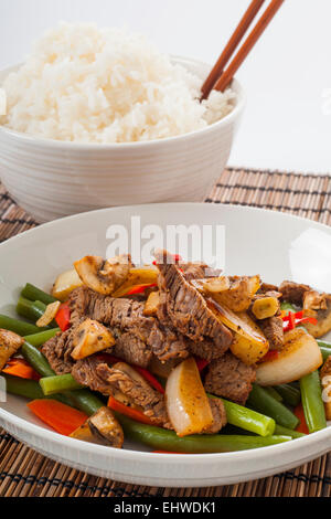 Repas maison de sautés, Pavé de boeuf, haricots verts, le poivron rouge, les champignons et les carottes avec du riz blanc, et baguettes Banque D'Images