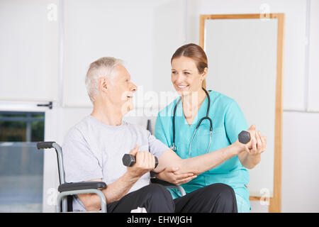 Vieil homme en fauteuil roulant levée haltères en physiothérapie Banque D'Images
