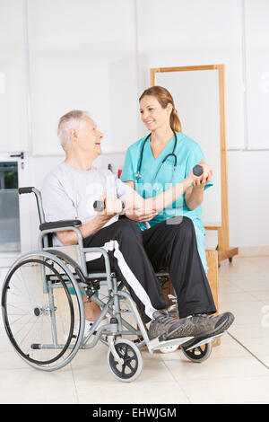 Senior man in wheelchair levée haltères en physiothérapie Banque D'Images