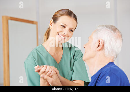 Smiling geriatric nurse holding hands with old man Banque D'Images