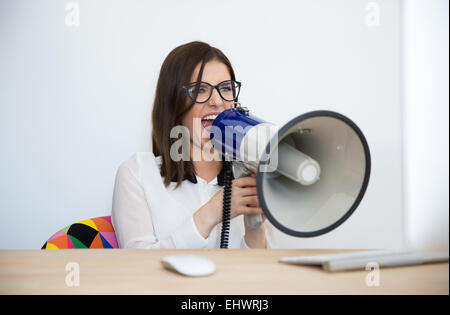 Businesswoman assis à la table et s'exprimant par mégaphone Banque D'Images