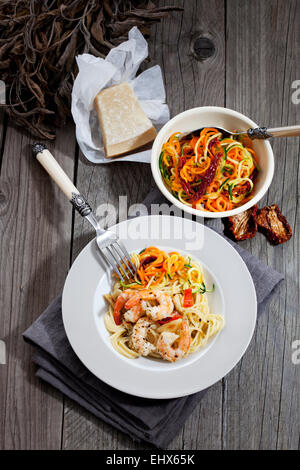 Spaghettis aux langoustines et légumes sur plaque, bol avec des spirales de tomates et courgettes, tomates séchées Banque D'Images