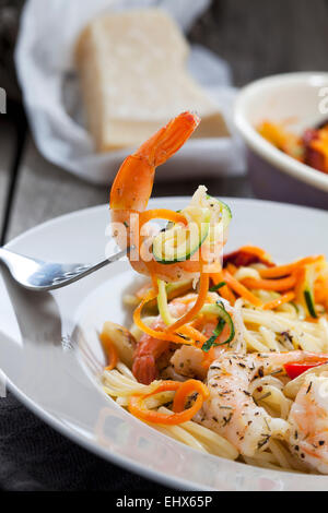 Spaghettis aux langoustines et légumes sur la plaque, les spirales de carottes et courgettes, fourche, close-up Banque D'Images