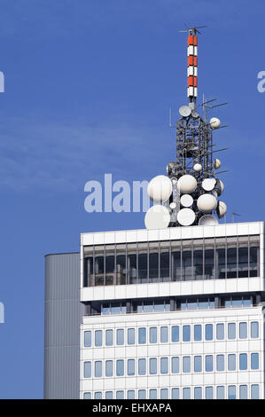 Grappe de différentes antennes micro-ondes en haut d'un immeuble de bureaux moderne élevé Banque D'Images