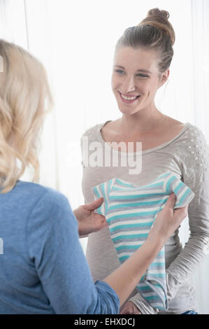 Deux femmes amie bébé clothes holding heureux Banque D'Images