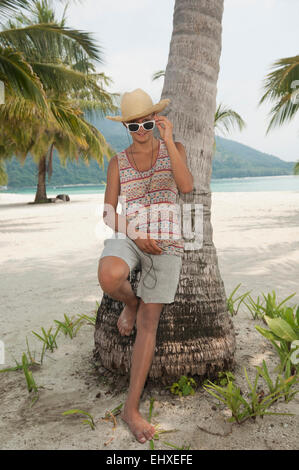 Teenage boy listening to music on the beach, Koh Lipe, Thaïlande Banque D'Images