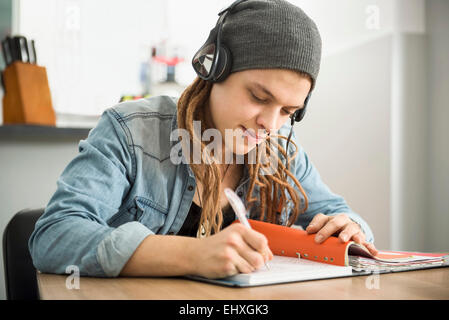 Jeune homme portant des écouteurs et d'étudier à la maison, Munich, Bavière, Allemagne Banque D'Images