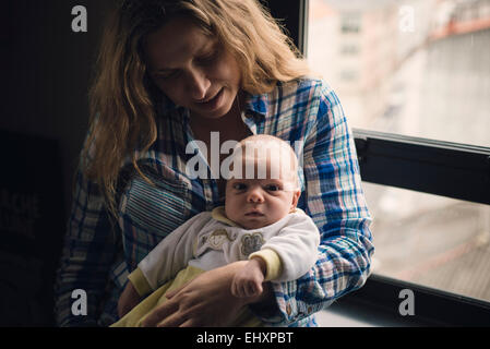 Portrait d'une mère avec son nouveau-né assis près d'une fenêtre Banque D'Images