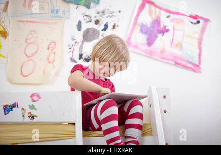 Petite fille assise sur un lit superposé, dessin sur le bloc de touches. Banque D'Images