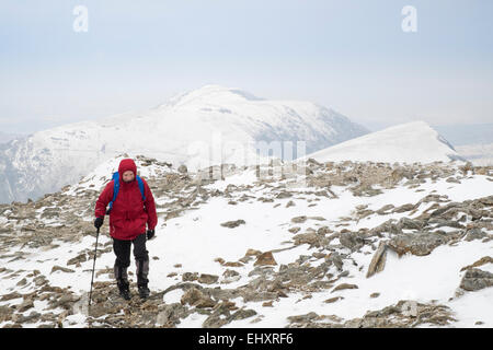 Male hiker en veste rouge de la randonnée dans la neige sur rocky Y Garn montagne dans le parc national de Snowdonia (Eryri). Ogwen, au nord du Pays de Galles, Royaume-Uni, Angleterre Banque D'Images