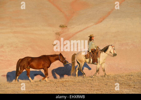 USA, Wyoming, cowgirl avec deux chevaux dans badlands Banque D'Images