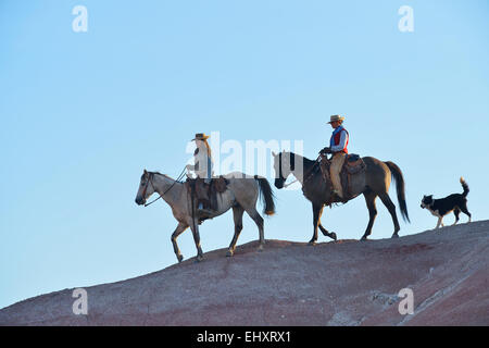 USA, Wyoming, deux cowgirls équitation et theit chien dans badlands Banque D'Images