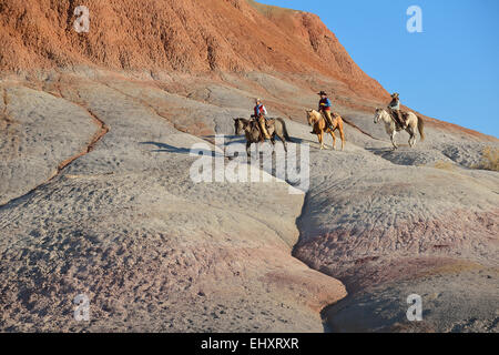 USA, Wyoming, deux cowgirls et un cowboy équitation dans badlands Banque D'Images