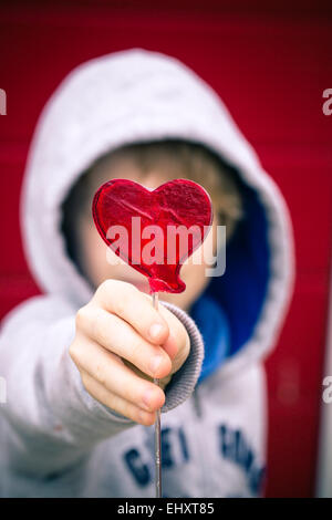 Boy holding heart-shaped lollipop Banque D'Images