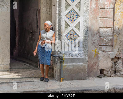 Une femme âgée cubain se trouve à l'extérieur de sa maison dans le quartier historique de La Havane en lumière spectaculaire. Banque D'Images