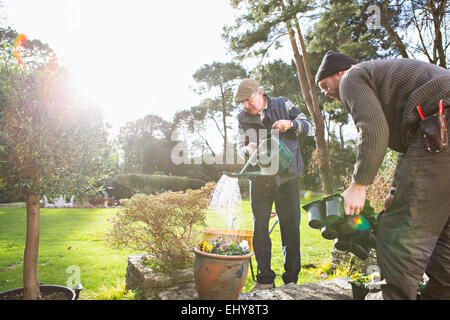 Senior man watering flowers in garden, Bournemouth, Dorset County, au Royaume-Uni, en Europe Banque D'Images