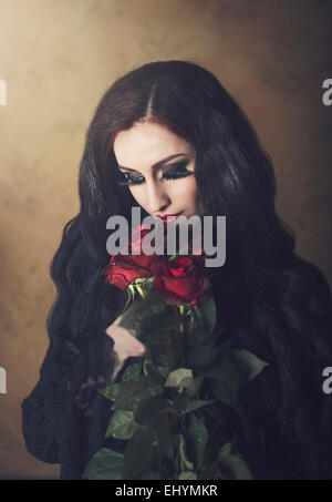 Portrait of a woman in black holding bouquet de roses rouges