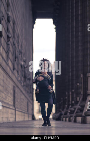 Mid adult woman carrying son fils, Paris, France Banque D'Images