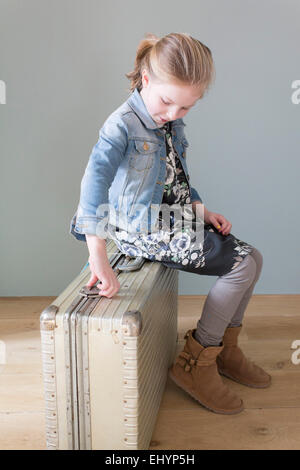 Girl sitting on suitcase Banque D'Images