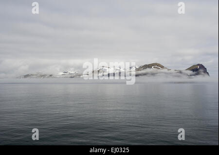 L'île de Jan Mayen entouré par les nuages et la brume avec seulement les montagnes visible Banque D'Images