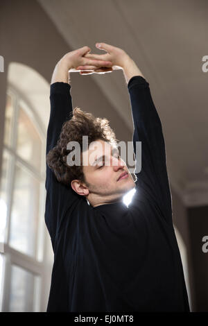 Beau jeune homme qui s'étend de mains au cours de sport Banque D'Images