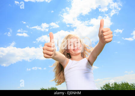 A smiling little girl in white blank t-shirt showing Thumbs up o Banque D'Images