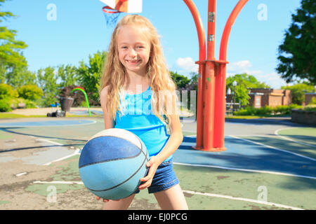 Petite fille jouer au basket-ball avec sur l'aire de jeux Banque D'Images