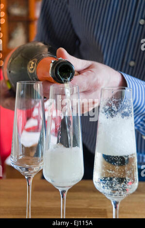 Portrait d'un homme vertical pouring champagne into flutes à Noël. Banque D'Images