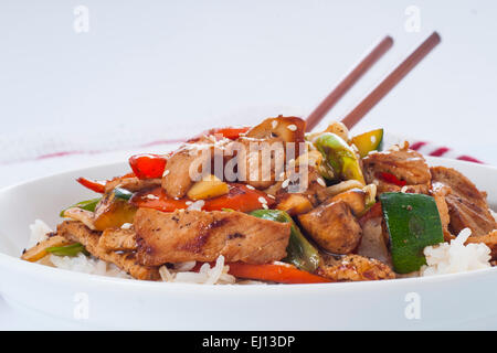 Bol de porc fait maison et des légumes sautées sur un bol de riz blanc, avec des baguettes Banque D'Images