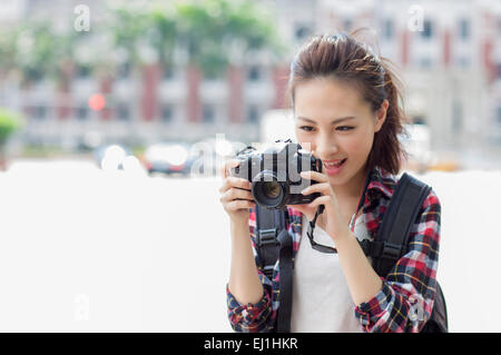 Young woman holding digital camera avec sourire, Banque D'Images