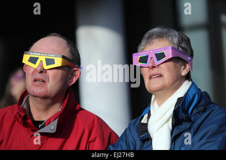 Sur la photo : Un homme et une femme regarder l'éclipse solaire du Waterfront Museum à Swansea, Pays de Galles du sud. Vendredi 20 mars 2015 Re : Les gens dans la plupart des pays de l'UK ont profité d'une bonne vue de l'éclipse solaire, vendredi matin. L'éclipse était visible sur environ 08:22am. La prochaine éclipse partielle visible pour les personnes au Royaume-Uni n'arrivera pas jusqu'en août 2026. Le phénomène se produit lorsque la Lune passe entre le Soleil et la terre. Credit : D Legakis/Alamy Live News Banque D'Images