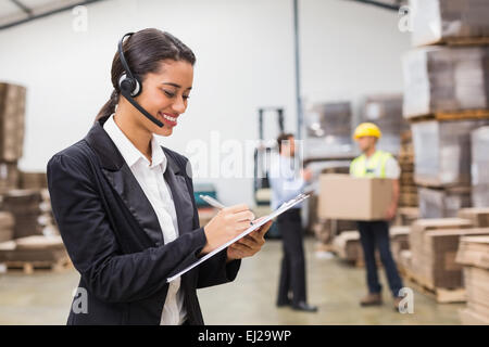 Warehouse Manager writing on clipboard Banque D'Images