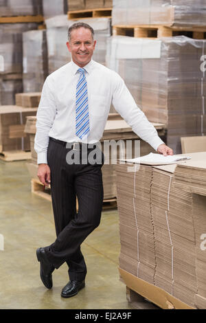 Patron souriant leaning on stack de cartons Banque D'Images